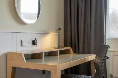 a desk in a room with a chair and a mirror at Holiday Inn Edinburgh Zoo by IHG in Edinburgh