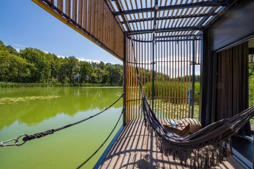 a hammock on a house with a view of a river at Water Hideout - Floating Villas in Wild Nature in Nowawieś Zbąska