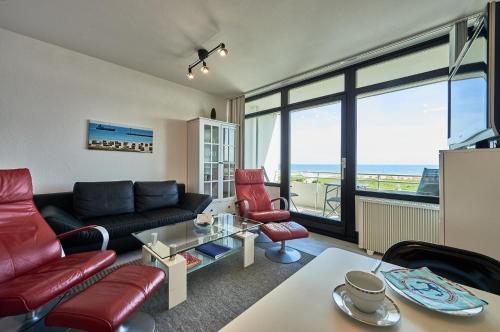 a living room with a black couch and red chairs at Stranddistel 7 Ostseezauber in Burgtiefe auf Fehmarn 
