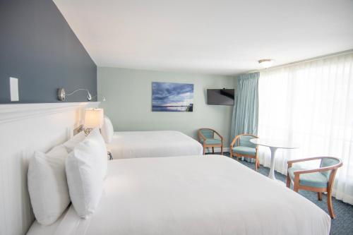 a hotel room with two beds and a table and chairs at Cape Colony Inn in Provincetown