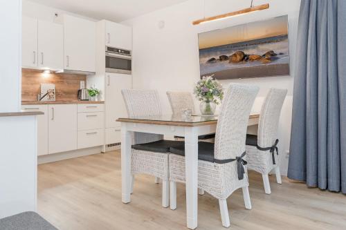 a white kitchen with a table and chairs at Wohnung 113 in Timmendorfer Strand