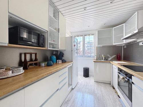 une cuisine avec des armoires blanches et un comptoir en bois dans l'établissement Appartement 6 personnes - Garage wilson, à Clermont-Ferrand