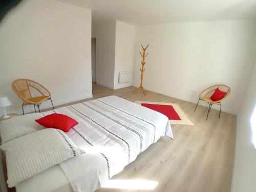 - une chambre avec un lit doté d'oreillers rouges et de 2 chaises dans l'établissement Appartement neuf dans domaine viticole, à Montagnac