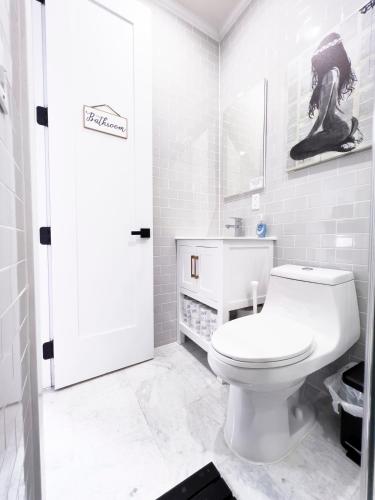a white bathroom with a toilet and a sink at The Chauncey House in Brooklyn