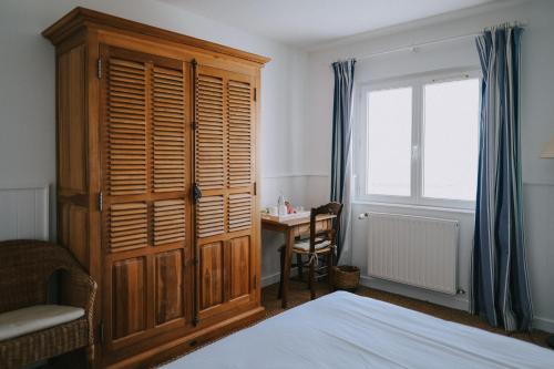 a bedroom with a wooden cabinet and a desk and a bed at Rivage, Chambres et Table in Saint-Pierre-Quiberon