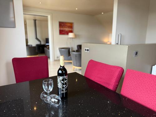 a bottle of wine sitting on a table with a wine glass at Holiday Park La Sapinière in Hosingen