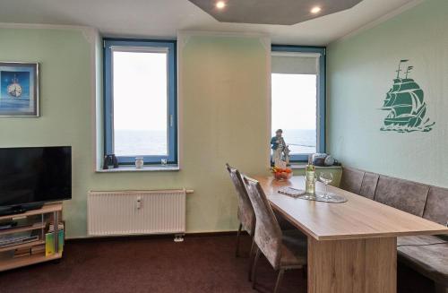 a dining room with a table and a ship on the wall at Am Südstrand 9 Strandburg I in Fehmarn