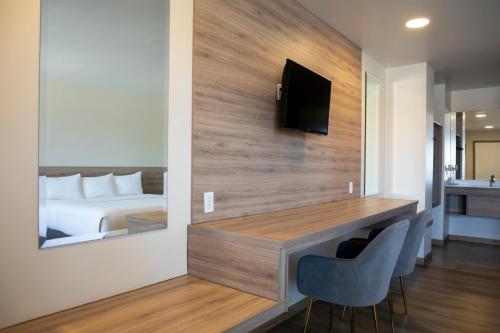 a hotel room with a bed and a desk with chairs at La Huerta Inn & Suites in Cuauhtémoc