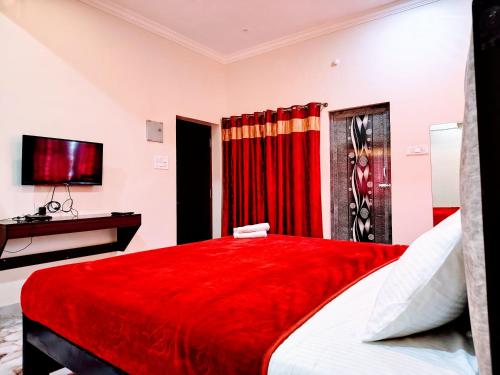 a bedroom with a red bed and a television at BYB Boutique Hotel in Thanjāvūr