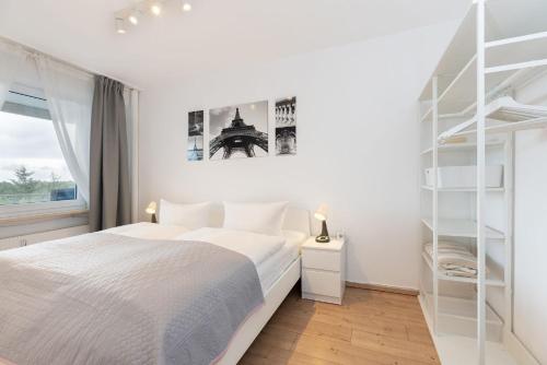 a white bedroom with a bed and a book shelf at Hanseat Wohnung 185 in Grömitz