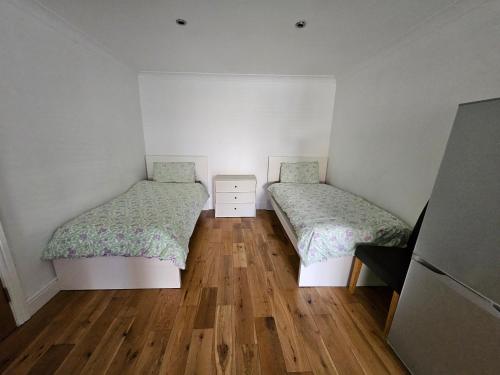 two beds in a small room with wooden floors at SnoozeDen Westmead - Windsor Castle & Legoland in Windsor