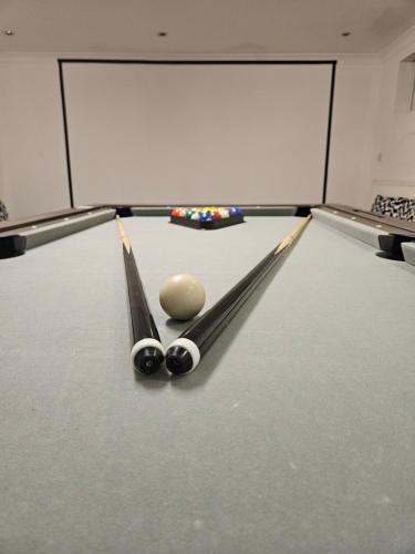 a snooker table with two cue sticks and a ball at SnoozeDen Westmead - Windsor Castle & Legoland in Windsor