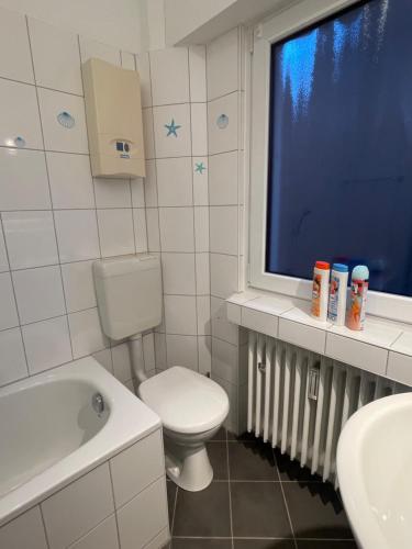 a bathroom with a toilet and a sink and a window at Cozy Private Rooms in Wesseling in Wesseling