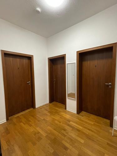 an empty room with three doors and wooden floors at Cozy Private Rooms in Wesseling in Wesseling