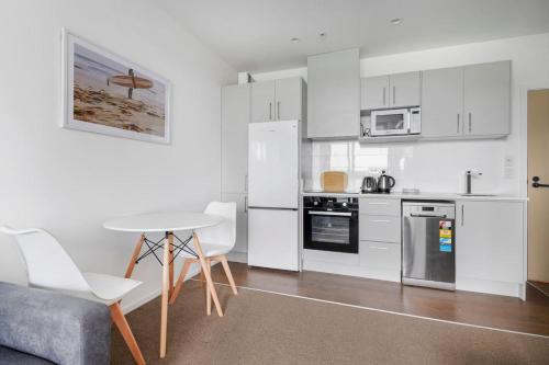 a kitchen with white appliances and a table and chairs at Neighborhood Hideaway with Air-con and Deck in Auckland