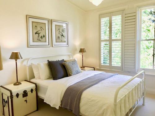 a bedroom with a white bed and two windows at Mirrabella Blue Mountains Boutique Getaway in Blackheath