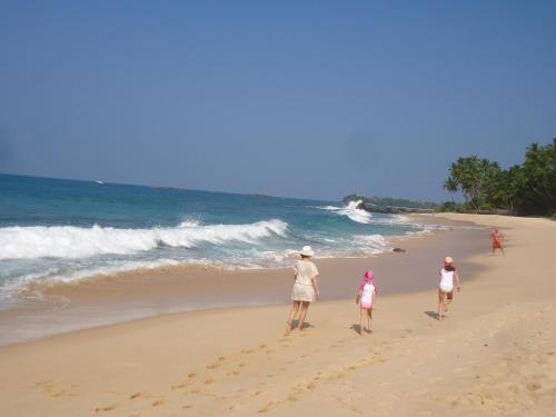 um grupo de pessoas caminhando na praia em Disa Residence em Galle