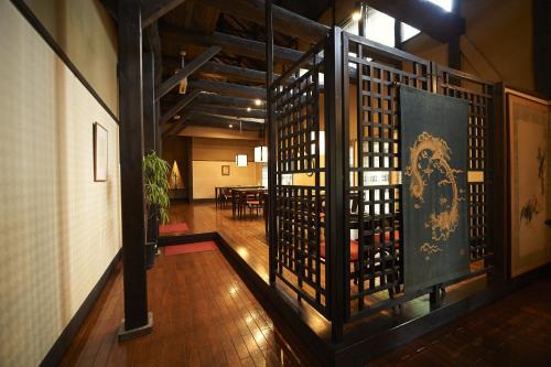 a room with a wooden floor and a wall with a gate at Hotel Kazahaya in Hita