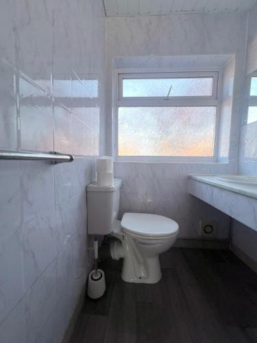 a white bathroom with a toilet and a window at Charming 2 bedrooms flat Skegness F11 in Skegness