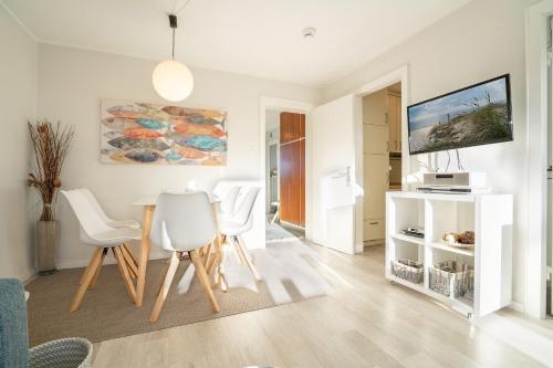 a living room with a dining room table and white chairs at Strandschloss Wohnung 40 in Grömitz