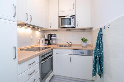 a white kitchen with a sink and a microwave at Strandschloss Wohnung 40 in Grömitz