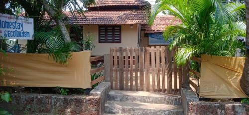 a house with a fence and palm trees in front of it at Kadingis homestay and eco tourism in Kadalundi
