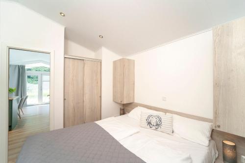 a bedroom with a large white bed and a hallway at Ferienhäuser Lübecker Bucht Ferienhaus Strandläufer in Haffkrug