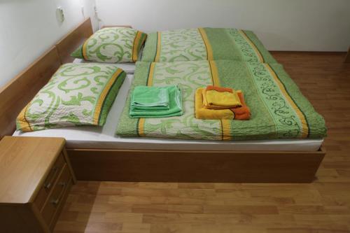 a bed with a green comforter and two towels at Villa Paris in Piešťany