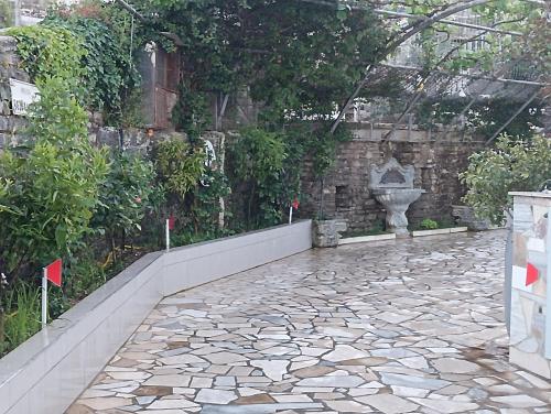 a garden with a stone pathway and a glass greenhouse at Guest House Bake in Gjirokastër