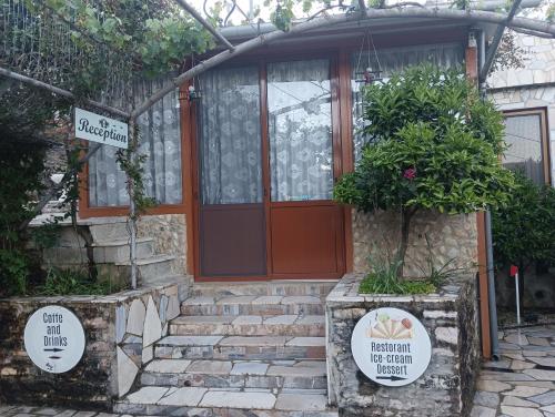 a house with a red door and some plants at Guest House Bake in Gjirokastër