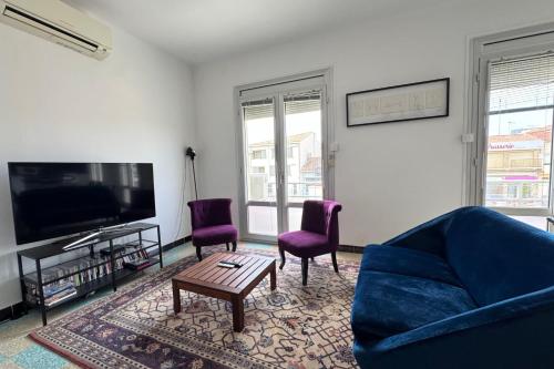 - un salon avec un canapé bleu et deux fauteuils violets dans l'établissement Place de l'Ancre Appartement 3 chambres avec garage 5 min plage & centre, au Grau-du-Roi