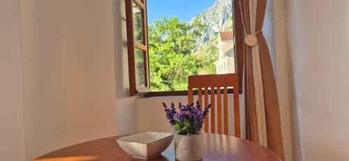 a table with a vase of purple flowers on it at Gospar Apartments in Kotor