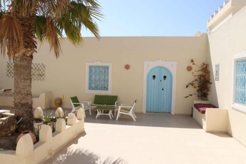 a patio with a blue door and a palm tree at Dar El Jerbiya in Midoun