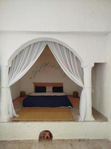 a bedroom with a bed with a white canopy at Dar El Jerbiya in Midoun
