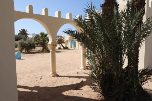 a building with arches and a palm tree in the desert at Dar El Jerbiya in Midoun