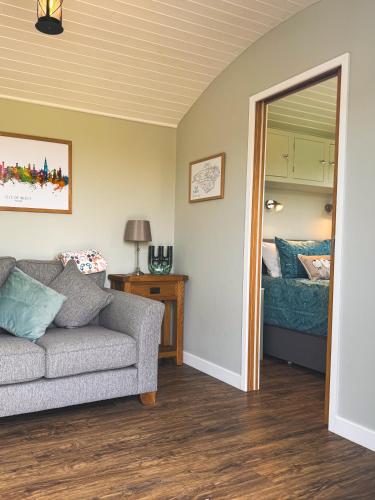 a living room with a couch and a mirror at Brambles, Shepherds Hut, Isle of Wight in Godshill