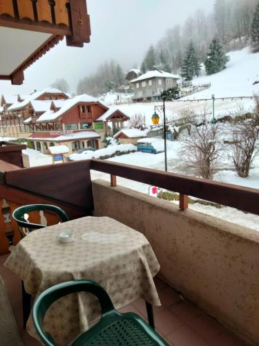 d'une table et de chaises sur un balcon avec une cour enneigée. dans l'établissement Studio n5 La cascade, à Bellevaux