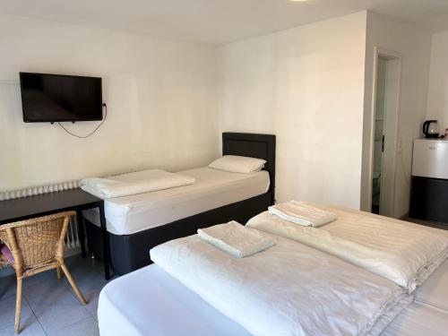 two beds in a room with a desk and a tv at Hotel Garni Emir in Cologne