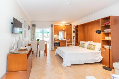 a bedroom with a white bed and a kitchen at Quinta Velha Oasis, Pool Resort in Cabanas de Tavira