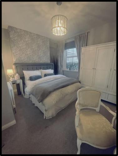 a bedroom with a large bed and a chair at Coastal Cwtch in Moffat