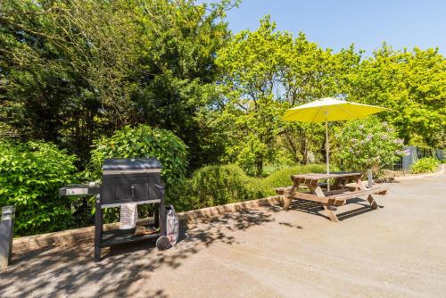 - un barbecue et une table de pique-nique avec un parasol dans l'établissement Havre de paix a 5 minutes de la mer a Etables, à Les Valoyens