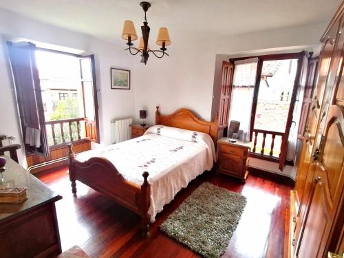 a bedroom with a bed and a chandelier and windows at El Resbalón in Comillas