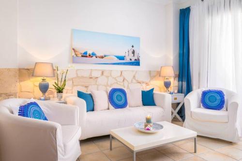 a living room with white furniture and blue pillows at Villa Blue Lagoon in Afitos