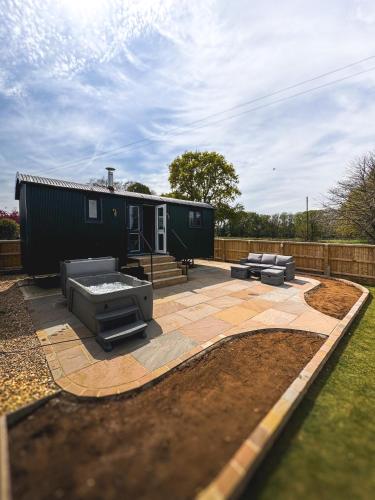 a backyard with a tiny house with a patio at Brambles, Shepherds Hut, Isle of Wight in Godshill