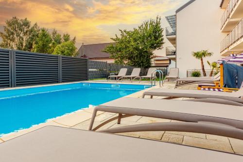 a swimming pool with lounge chairs next to a building at KASHUBIAN Resort in Władysławowo