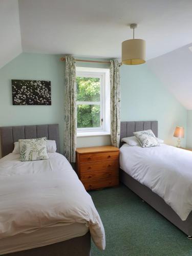 two beds in a room with a window at Kirkwood - Real Farm Holidays & Experiences in Dalton