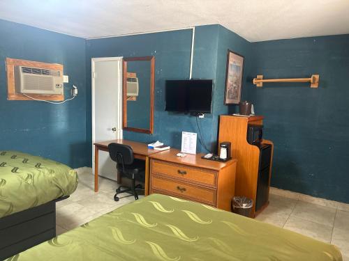 a bedroom with a bed and a desk with a computer at Budget Inn in Nocona