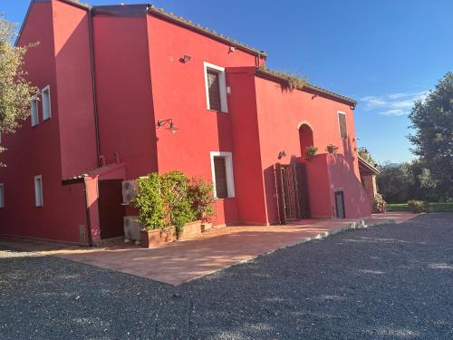 a red building with a driveway in front of it at Bio Agriturismo Il Melograno di Banditella Ristorante in Alberese