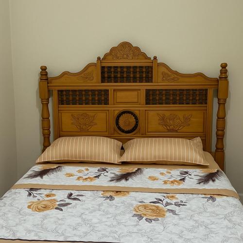 a bed with a wooden headboard with flowers on it at Résidence Kawtar Meknès in Meknès