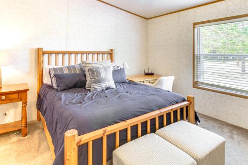 1 dormitorio con cama de madera y ventana en Tenstrike Lake House on 60 Acres Hike and Fish!, en Tenstrike